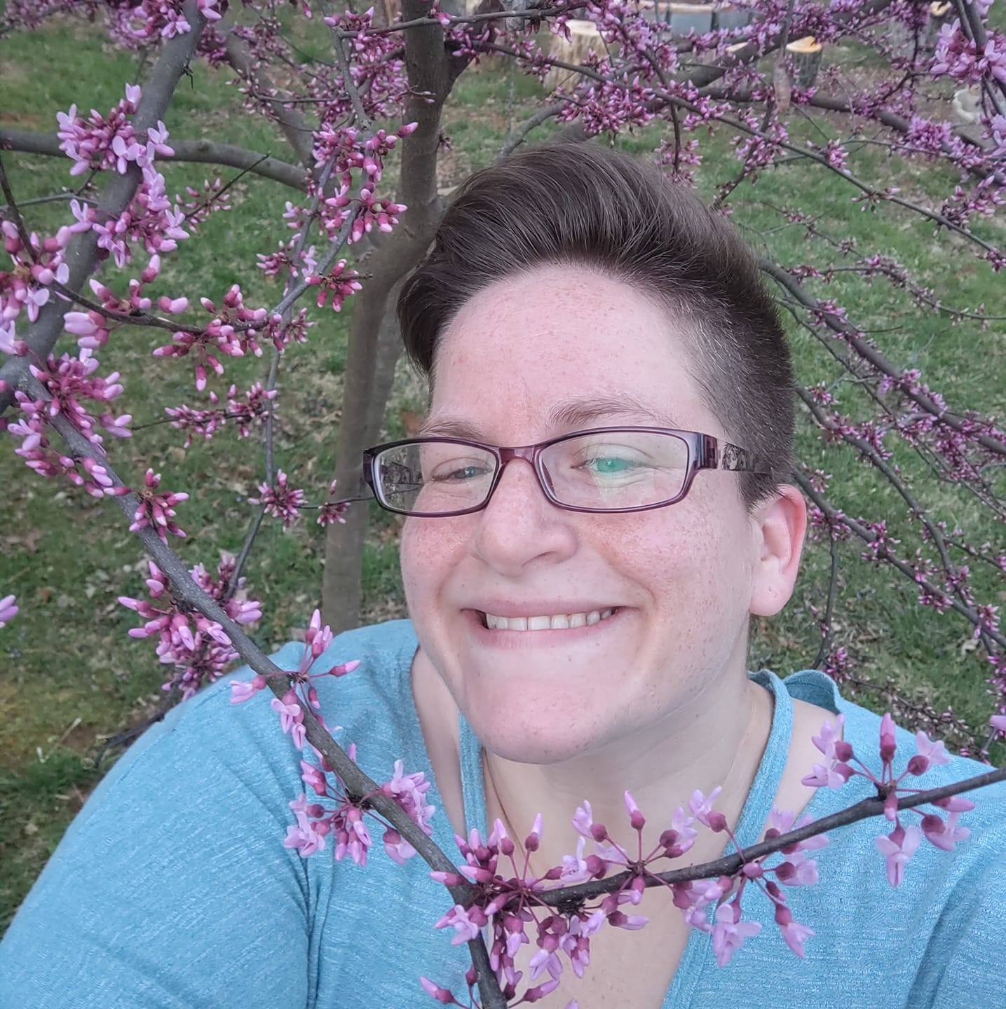 Hannah Bement smiling at the camera from under flowering branches.