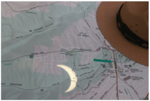 A ranger's hat and a projected image of the eclipsed Sun lie on a map of Hot Springs National Park.