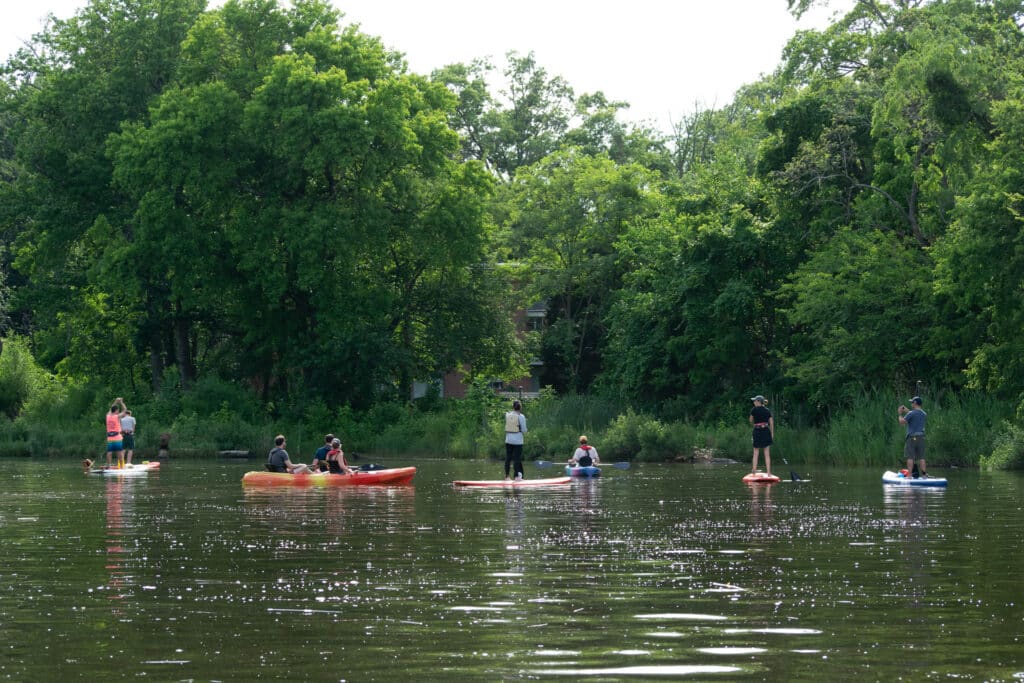 Group of 9 people on the water in kayaks or on stand up paddleboards